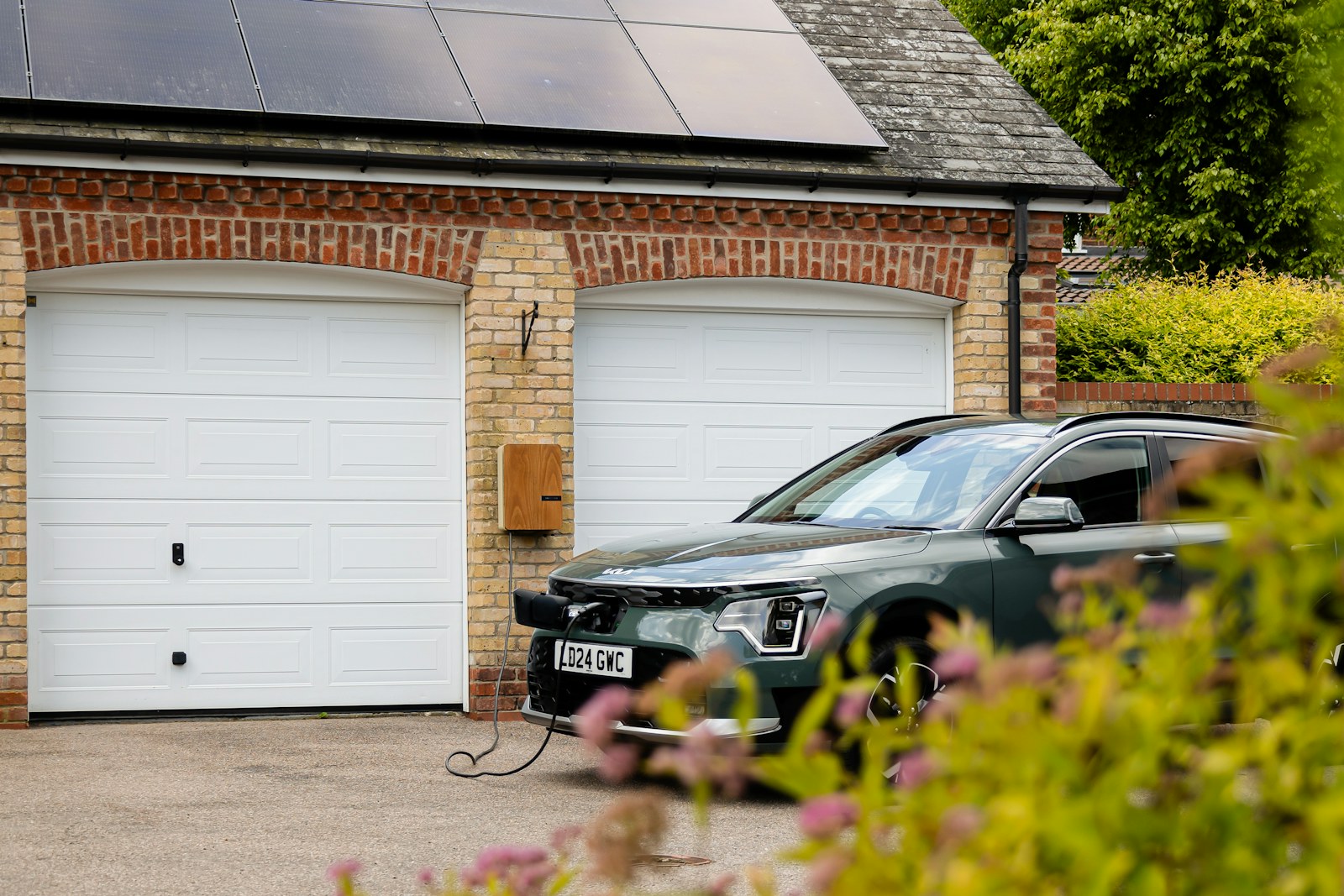 Elektrische auto aan een laadpaal voor een garage met zonnepanelen