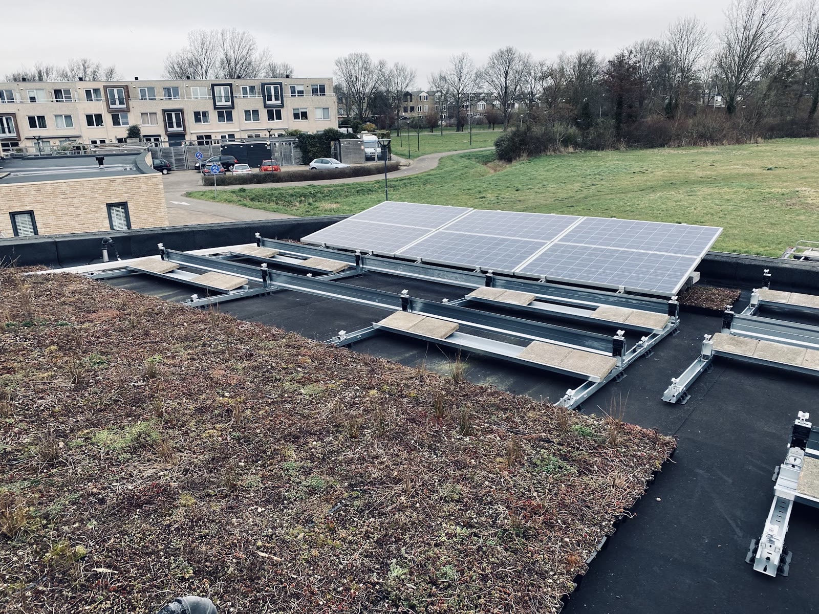 Zonnepanelen op een plat groen dak in oost-westopstelling
