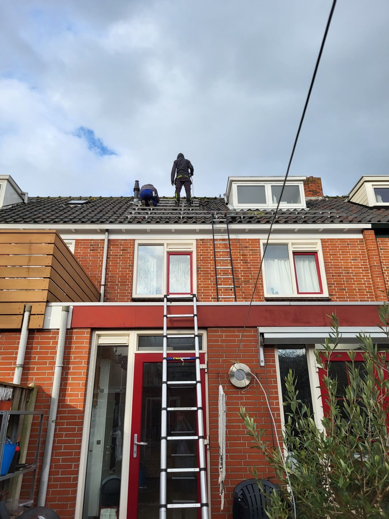 Monteur op het dak van een woning met ladder