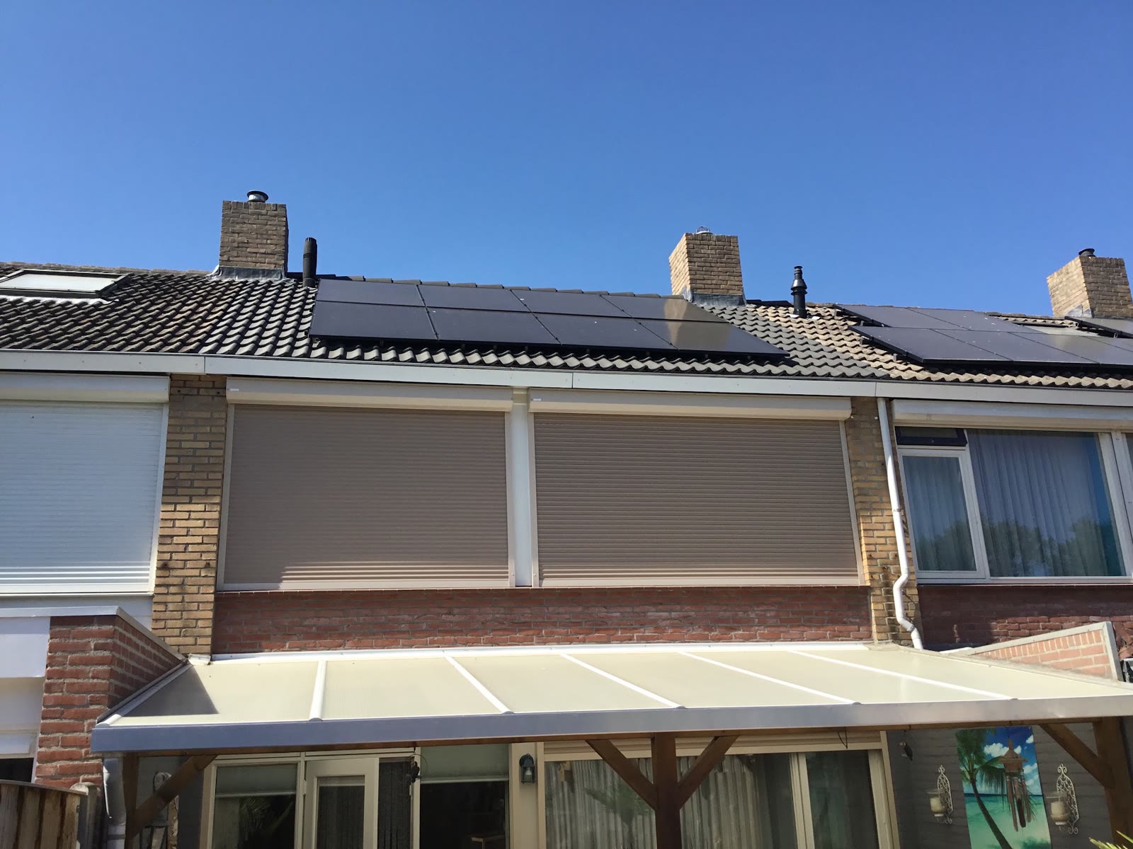 Zonnepanelen op een rij woningen onder een blauwe lucht