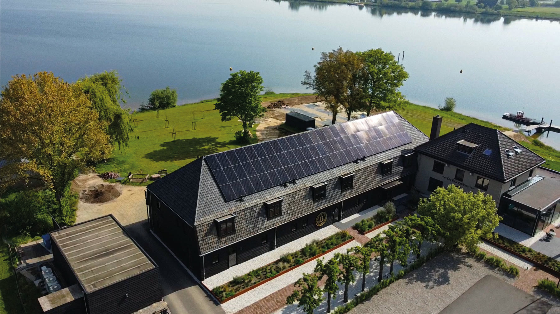 Luchtfoto van een bedrijfspand met zonnepanelen aan het water